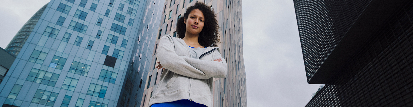 Mujer con los brazos cruzados en la calle con edificios altos de fondo