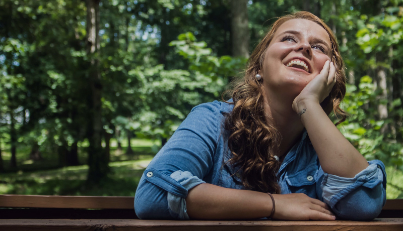 Mujer feliz y emocionada en el bosque