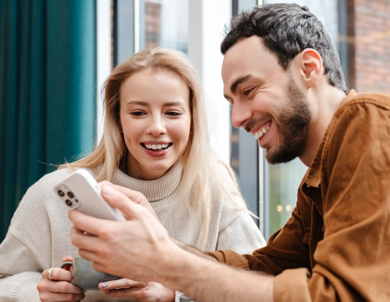 Dos personas riéndose mientras ven algo juntos en un iPhone