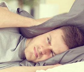 Persona molesta tapándose los oídos con la almohada