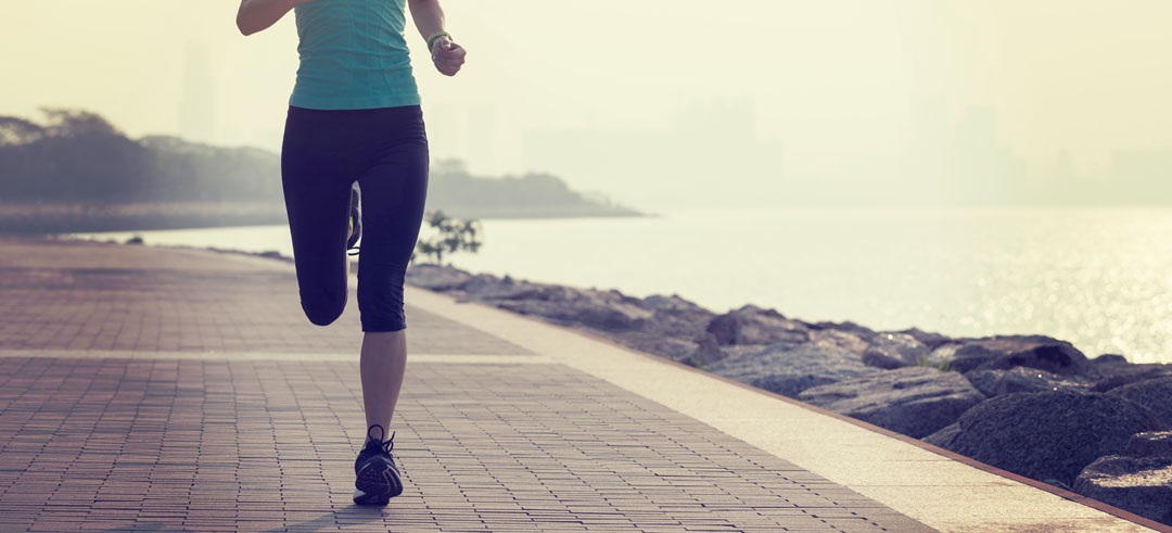 Mujer corriendo por un paseo marítimo cerca de la playa